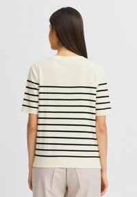 Suéter blanco de manga corta con franjas horizontales negras, neckline redondeado, dobladillo acanalado y puños. Textura suave, ajuste casual.