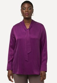 Paarse blouse met lange mouwen en een strik-kraag, gemaakt van gladde stof, met een ontspannen pasvorm en manchet bij de polsen.