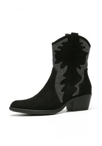 Botas de vaquero de ante negro con costuras decorativas y acentos de tachuelas plateadas; presentan una puntera puntiaguda y un diseño de tacón cuadrado.