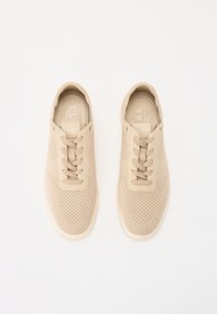 Sneakers beige con tomaia in mesh, punta rotonda e lacci piatti. Presentano una linguetta imbottita e una soletta ammortizzata, con un design minimalista.