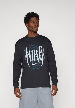 Zwarte lange mouw T-shirt met "NIKE" in gestileerd witte en blauwe lettertype tegen een mesh achtergrond. Gemaakt van katoen, heeft het een relaxte pasvorm.