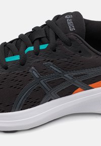Baskets de sport noires avec une tige en maille texturée, des accents gris et orange, et une semelle blanche. Présente une bande bleu-vert et un talon renforcé.