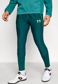 Τζελ αθλητικό παντελόνι με κίτρινες λεπτομέρειες και λογότυπο Under Armour. Κατασκευασμένο από απαλό, ελαστικό ύφασμα με στενή εφαρμογή και υφασμάτινες υφές στα κάτω τμήματα.