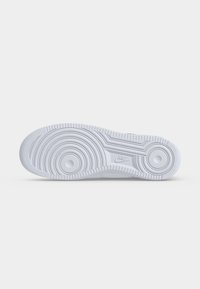 Λευκή σόλα παπουτσιού Nike με κυκλικά σχέδια πρόσφυσης και ανάγλυφο λογότυπο Nike στο κέντρο, φωτογραφημένη σε απλό φόντο.