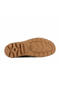 Suela de goma marrón con un patrón de relieve texturizado, que presenta acanaladuras y recortes circulares para mayor agarre y flexibilidad. Logo del fabricante visible.