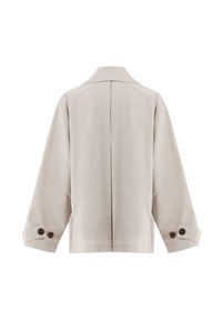 Veste beige à manches longues avec une couture centrale dans le dos et des poignets à boutons, présentée sur un fond blanc.