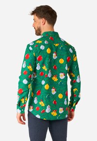 Maglietta verde a maniche lunghe con una stampa festiva di pupazzi di neve, ornamenti e alberi di Natale. Tessuto di cotone con una superficie liscia.