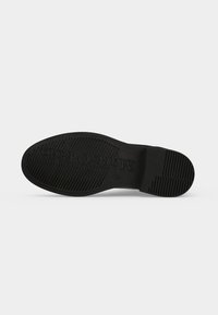 Semelle de chaussure noire avec motifs de grip texturés et le nom de la marque "Matteo Orofolo" embossé au centre.