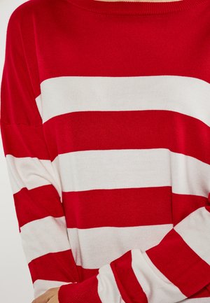 Rood-wit gestreepte sweater met lange mouwen, geribbelde halslijn en een zachte textuur. De strepen zijn gelijkmatig verdeeld, wat een gedurfde patroon creëert.
