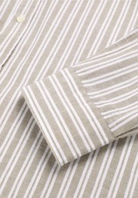 Camicia a righe beige e bianche con dettagli a bottoni, realizzata in un tessuto texture, maniche lunghe e polsini che mostrano chiaramente il motivo a righe.