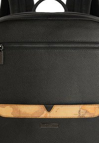 Zaino in pelle nera con superficie testurizzata, tasca anteriore con zip e una fascia decorativa in pelle beige con motivo mappa.