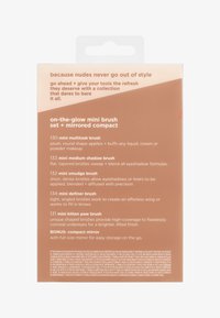 Sminkebørstesett med emballasje som viser fem mini-børster og et kompakt speil med beskrivelser av børsteformer og bruksområder.