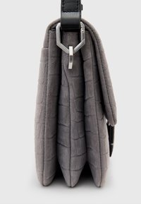 Szara torebka z faux zamszu o fakturze krokodyla, z czarnym skórzanym paskiem i metalowym zapięciem. Trzy strukturalne fałdy tworzą kompaktowy design.