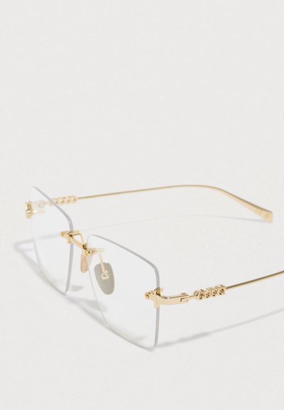 Arany színű, fémvázú napszemüveg átlátszó lencsékkel. Négyzet alakú, minimalista design, apró fém díszítésekkel és orrtámasszal.