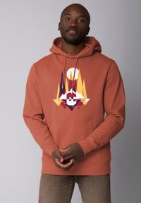 Roestkleurige hoodie van zacht materiaal, met een geometrisch bergontwerp in crème, geel en paars. Inclusief kangoeroezak.