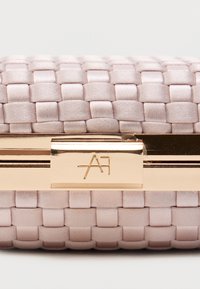 Πλεκτός φάκελος σε ανοιχτό ροζ με λείο υφή, με κούμπωμα σε χρυσό τόνο και ανάγλυφη λεπτομέρεια λογότυπου στο κούμπωμα.