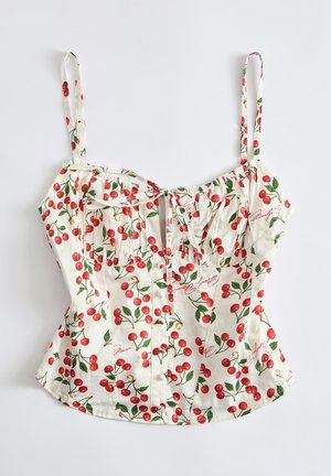 Top corto bianco senza maniche con spalline regolabili, decorato con motivi di ciliegie rosse e foglie verdi, con dettaglio annodato sul davanti.