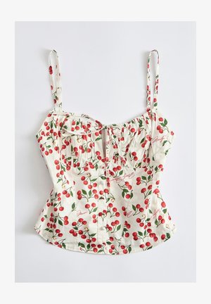 Top corto bianco senza maniche con spalline regolabili, decorato con motivi di ciliegie rosse e foglie verdi, con dettaglio annodato sul davanti.