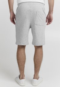 Shorts griș din bumbac cu un talie elastică, buzunar posterior și o croială lejeră, care se termină puțin peste genunchi. Tenisi albi completează ținuta.