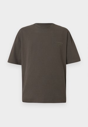 Camiseta de gran tamaño color marrón oscuro, hecha de algodón, con mangas cortas y cuello redondo, con un logo sutil en el frente.