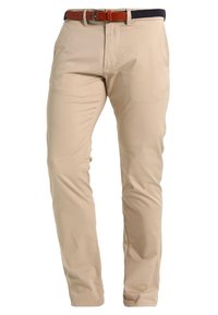 Beiga bomullbyxor med rak passform, som har en midja i mörk marinblått tyg och ett bälte i brunt läder. Slät yta, inga synliga mönster.