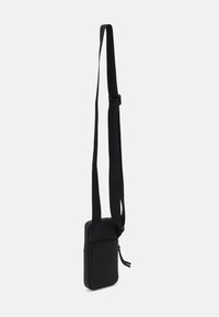 Borsa a tracolla nera compatta con una superficie morbida e testurizzata, tracolla regolabile e una tasca frontale. Forma rettangolare, design minimalista.