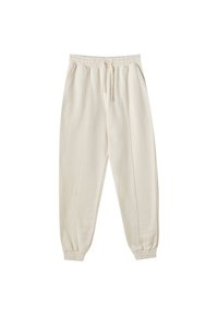 Pantalon de jogging beige avec taille et poignets élastiques, poches avant et coutures visibles le long des jambes.