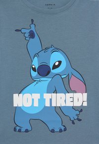 Blauwe katoenen t-shirt met een cartoonfiguur met grote oren en expressieve ogen, tekst "NIET MOE!" in vetgedrukte witte letters op de voorkant.