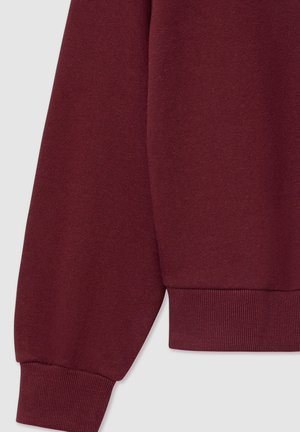 Felpa bordeaux con polsini a coste, texture del tessuto morbida e vestibilità comoda, che mette in evidenza un design liscio e senza cuciture.