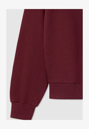 Burgundowy sweter z ribbowanym mankietem, miękką teksturą materiału i luźnym krojem, prezentujący gładki, bezszwowy design.