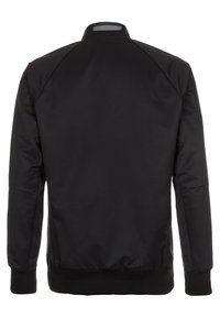 Sort bomberjakke med en glat, mat finish. Har en ståkrave, ribbede manchetter og kant. Enkel design uden synlige mønstre eller accenter.