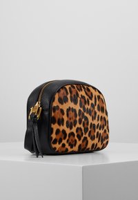 Kočičí vzor srst na jedné straně, hladká černá kůže na druhé straně, se zlatým zipem a ozdobou v podobě třásně. Klasický kulatý tvar.