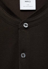 Top slim-fit de culoare maro închis, cu o țesătură texturată, guler rotunjit și două închideri cu nasturi. Eticheta arată informațiile despre marcă și mărime.