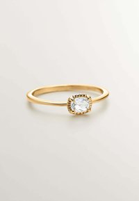 Anillo de oro con una piedra clara en corte cojín, rodeada de un engaste estriado, con una banda lisa y redondeada.