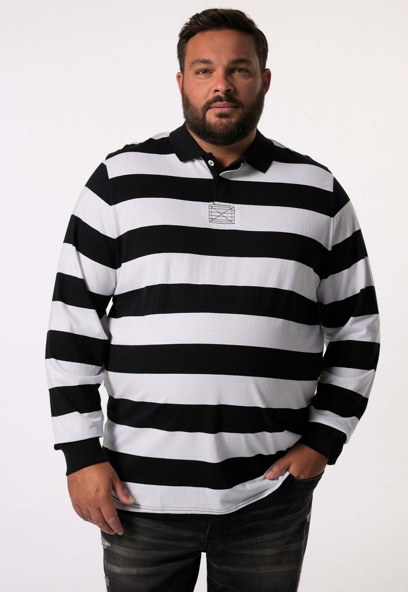 Musta-valkoinen raidallinen pitkähihainen polo-paita, jossa on kaulus ja pieni brodeeraus rintataskussa. Yhdistetty tummiin farkkuihin.