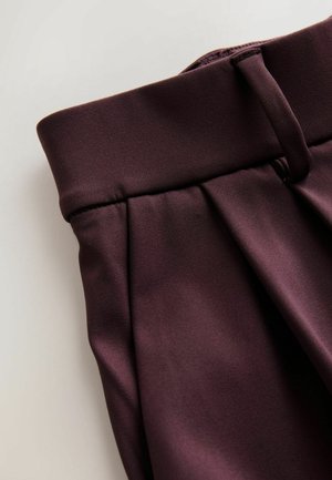 Bordo spalvos audinio kelnės su plačiu juosmeniu, klostuotu priekiu ir lygiu paviršiumi. Turi diskretiškus siūlus ir švarų apdailą.