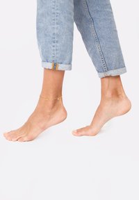 Anklet koosneb õrnast kuldse ahelaga, millel on väikesed ringikujulised aktsendid. Kandmiseks paljal jalal, koos üles keeratud helesiniste teksadega.