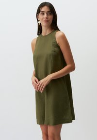 Ärmelloses, olivgrünes Kleid in lockerer Passform. Hergestellt aus strukturiertem Stoff mit einem leicht längeren Saum hinten und einem runden Halsausschnitt.