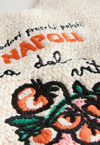 Sac en paille tissé avec des accents brodés colorés en orange, vert et rose. Le texte inclut "NAPOLI" en fil orange en gras.