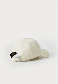 Beige keps med rund krona, slätt tyg, böjd skärm och justerbar metallspänne bak. Minimalistisk design.