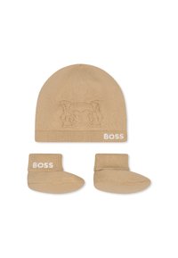 Bonnet en tricot beige avec un design animal en relief et un bord replié, associé à des bottines beiges assorties arborant le logo "BOSS" en blanc.