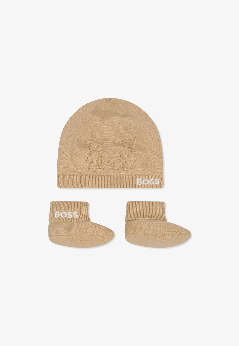 Bonnet en tricot beige avec un design animal en relief et un bord replié, associé à des bottines beiges assorties arborant le logo "BOSS" en blanc.
