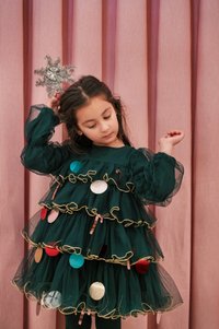 Zelena tulle obleka z prazničnimi okraski in zlatimi zaključki, ki ima naborke in dolge rokave; srebrna zvezda kot dodatak v laseh.