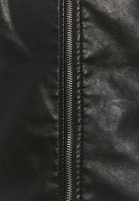 Sekce s černou koženou bundičkou ukazuje detailní záběr na zip, který má stříbrné kovové zuby a texturovaný povrch kůže.