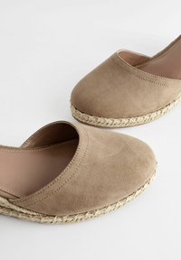 Beige semišové espadrilky s kulatou špičkou a elastickým otevřením, s tkanou juteovou podrážkou. Hladká vnitřní podšívka.