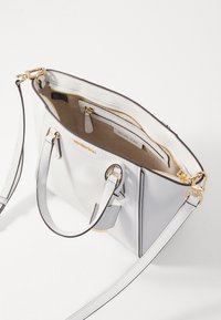Sac à main en cuir blanc avec quincaillerie dorée, doté de poignées supérieures doubles et d'une bandoulière réglable. Comprend un extérieur texturé et des compartiments zippés.