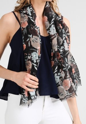 Châle à fleurs noir orné de fleurs pastel rose et bleu, bords frangés, porté sur un haut sombre, apporte douceur et texture.