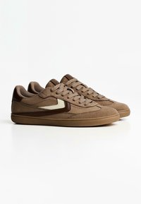 Brown suede sneakers with a rounded toe, textured panels, and tonal laces. Features a contrasting beige logo on the side and rubber outsole.