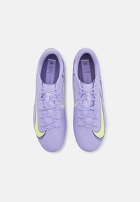 Paarse sportschoenen met een gestructureerde bovenkant, voorzien van een groene swoosh en veters, ontworpen voor prestatie. Labels zijn zichtbaar aan de binnenkant.