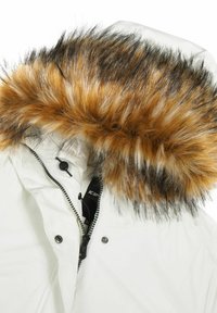 Giacca invernale bianca con cappuccio rimovibile, caratterizzata da un fitto bordo in pelliccia marrone e nera. Chiusura a zip con bottoni a pressione visibili.